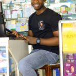 Jeune pharmacien africain souriant derrière le comptoir de sa pharmacie