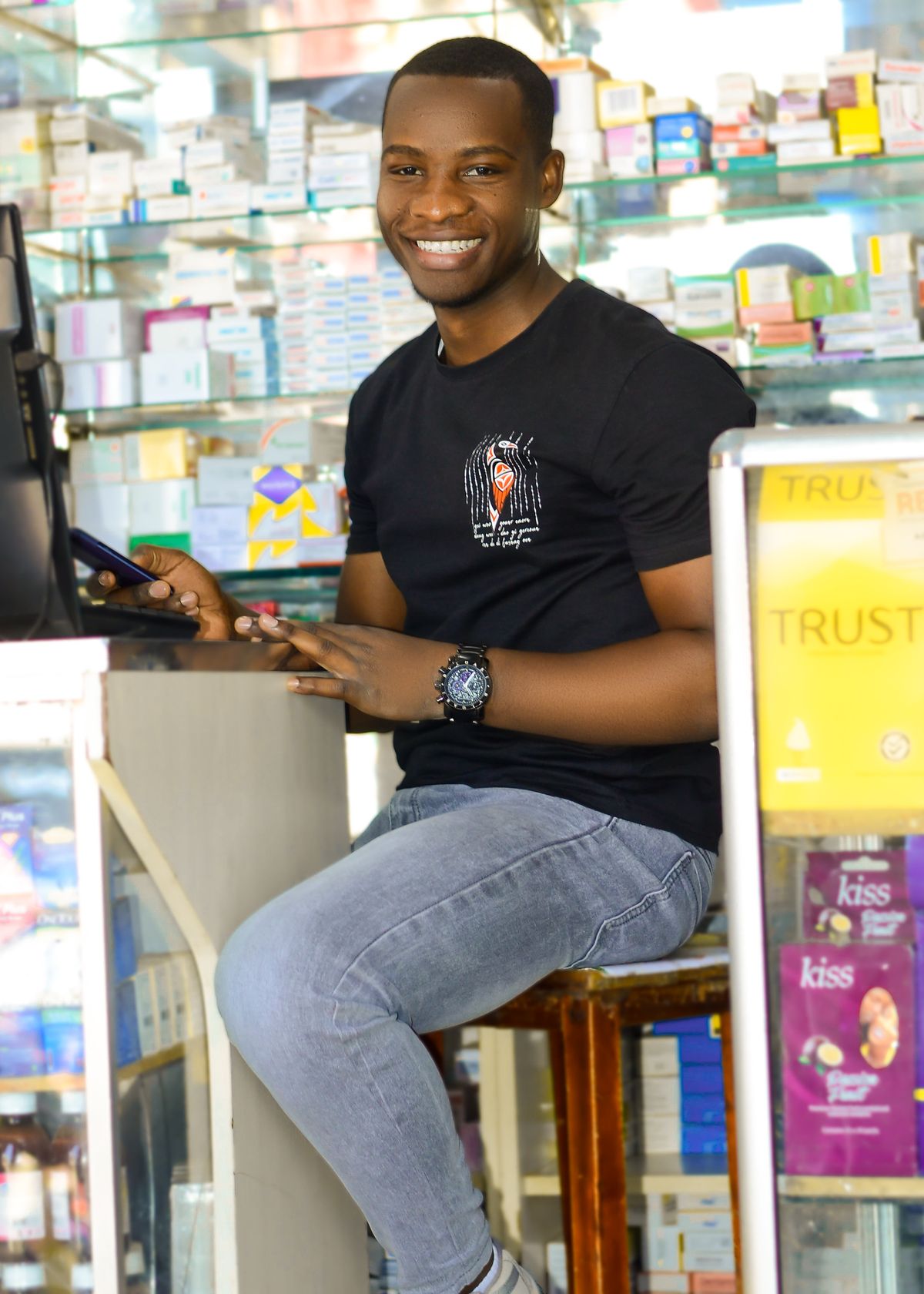 Jeune pharmacien africain souriant derrière le comptoir de sa pharmacie