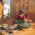 Une mère cuisine avec son enfant dans un village africain