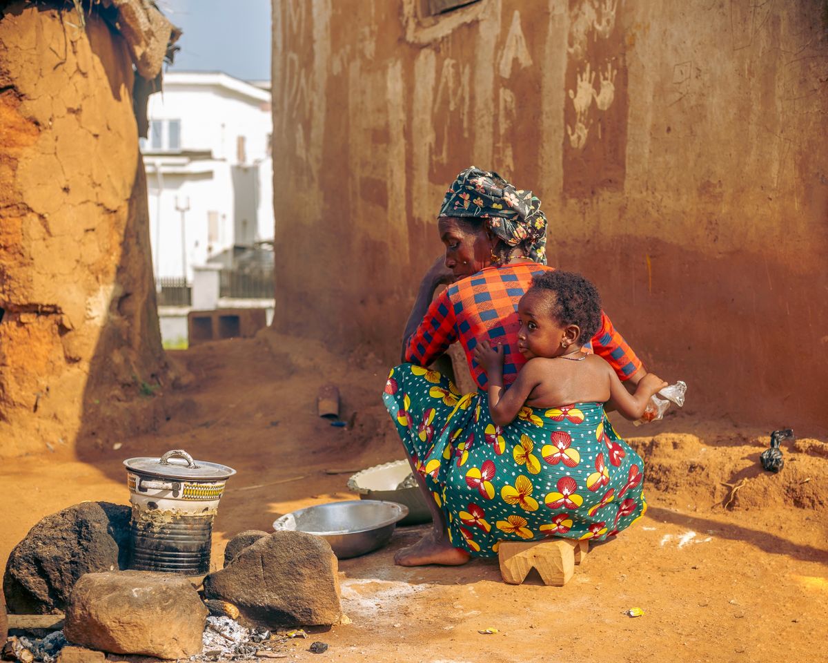 Une mère cuisine avec son enfant dans un village africain